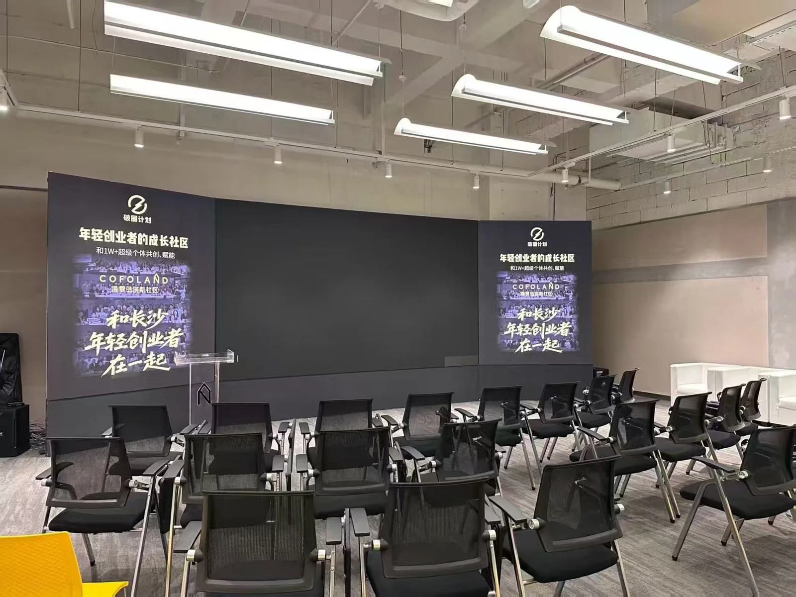 破圈计划路演厅，背景为「年轻创业者的成长社区」品牌主视觉与整齐座椅