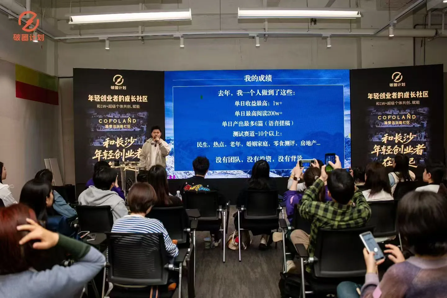 破圈路演现场,演讲者在投影前分享,观众聆听并举起手机拍摄